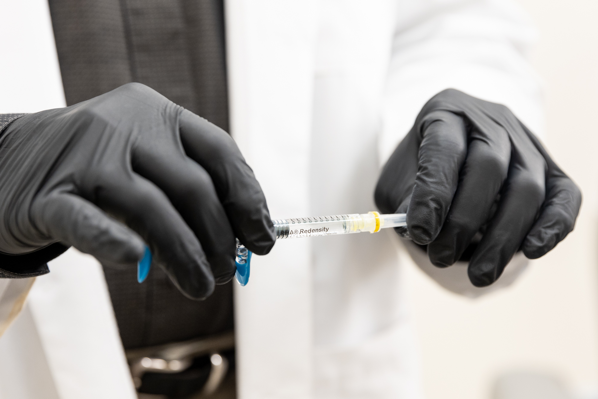 A provider at Enrichment Skin Solutions while wearing surgical gloves, holds a syringe of lip filler. Botox and fillers in Brooklyn Park treat different aesthetic concerns, and those who want to perfect their pout often opt for fillers.